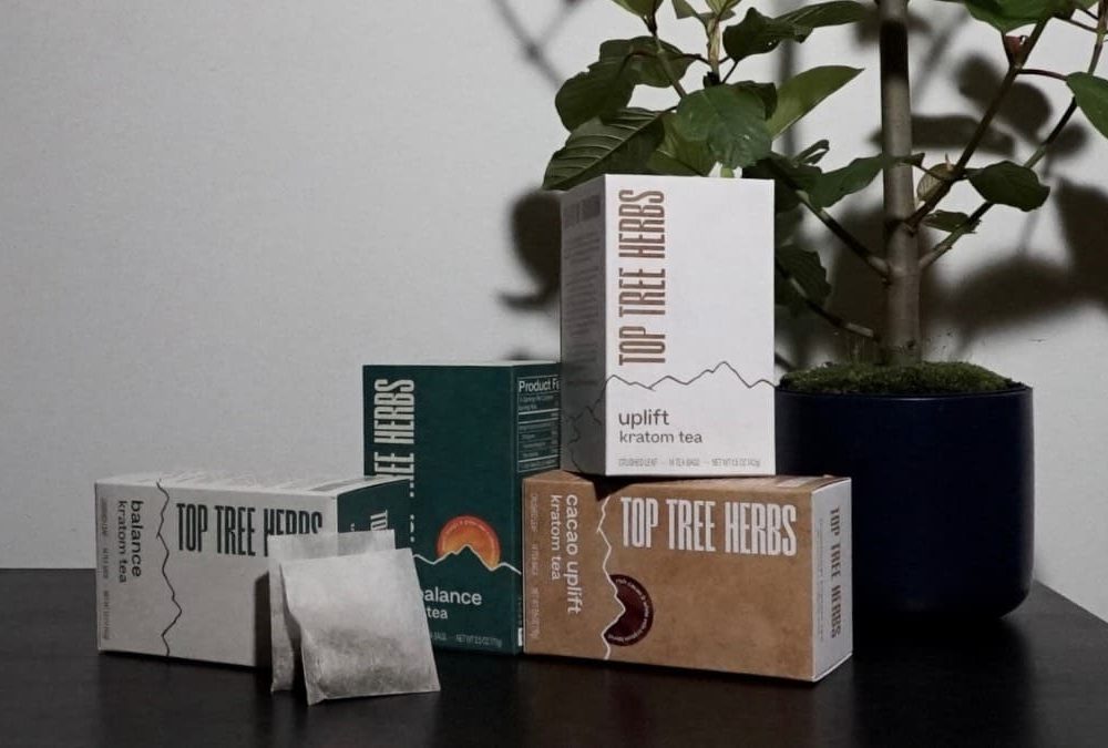 Kratom Strain Myths - Boxes of strain-free kratom tea in front of a kratom tree